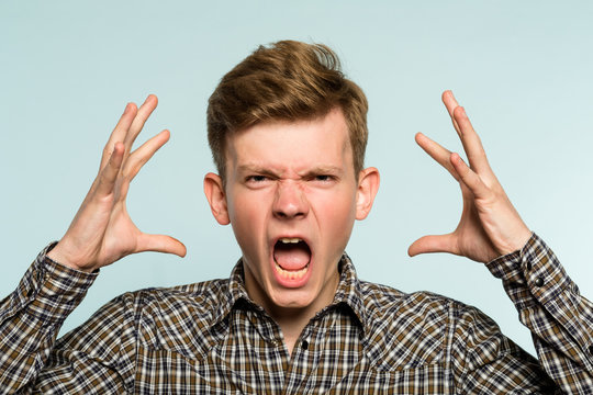 Emotional Breakdown. Angry Man In Distress. Agony And Rage Concept. Portrait Of A Young Guy On Light Background. Emotion Facial Expression. Feelings And People Reaction.