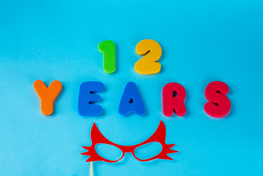 12 years old celebrating classic logo. Colored happy anniversary 12 th cute numbers on blue background. Greetings celebrates card. Traditional digits of ages. Flat lay .
