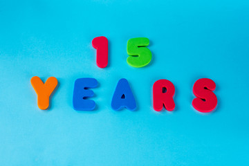 Naklejka premium 15 years old celebrating classic logo. Colored happy anniversary 15 th colored numbers on blue background. Greetings celebrates card. Traditional digits of ages. Flat lay .