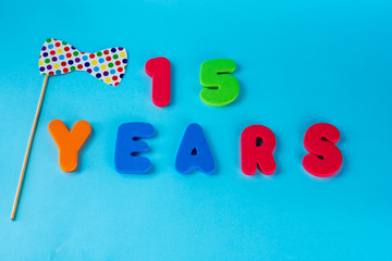 Naklejka premium 15 years old celebrating classic logo. Colored happy anniversary 15 th colored numbers on blue background. Greetings celebrates card. Traditional digits of ages. Flat lay .