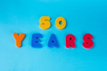 50 years old celebrating classic logo. Colored happy anniversary 50 th colored numbers on blue background. Greetings celebrates card. Traditional digits of ages. Flat lay .
