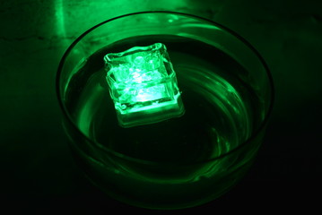 In a glass of champagne glass floats a green ice cube very stylish and beautiful