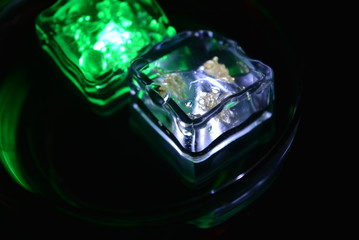 In a glass glass from under the champagne floats a green ice cube and a white ice cube is very stylish and beautiful