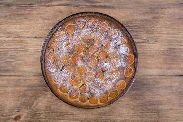 Homemade organic apricot pie dessert ready to eat . Apricot tart with walnut on wooden background, close up