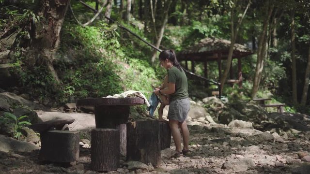 Asian mother dress her son about 2 year and 4 months old at waterfall in Asian countryside