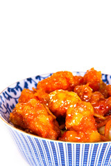 Orange Chicken with sesame seeds in a blue and white ceramic bowl.  Fast food takeout