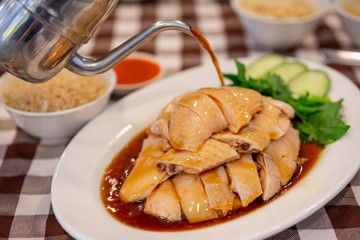 Asian Chinese food style Steam Chicken with Rice and sauce (Hainan Chicken) on white plate at Chinese restaurant in Singapore