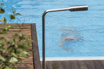 A man floating under water in an outdoor pool.
