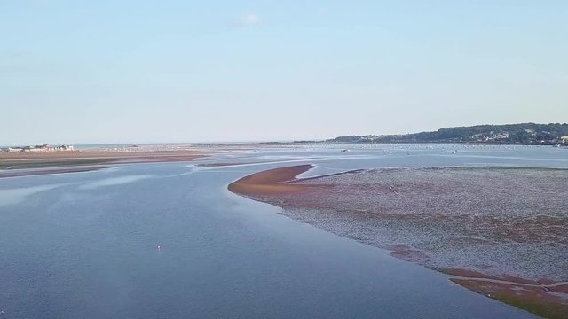 Day time drone flying over the beautiful coastal town of Lympstone England. The sky is clear, the water is calm and blue, and the land is amazingly breathtaking.