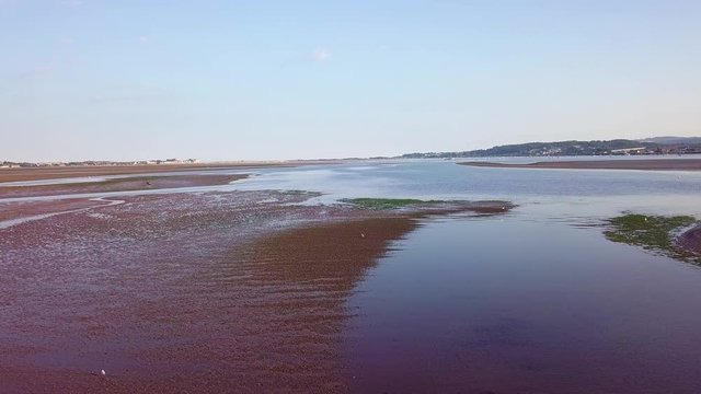 Drone gliding over the water off of the coast of Lympstone England. Water plants as well as wildlife is visible from the sky.