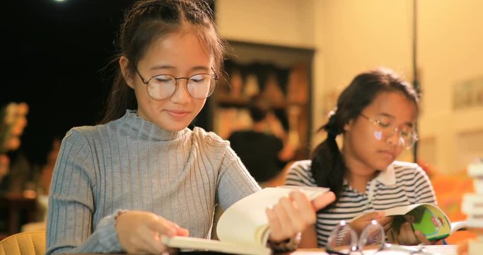 asian teenager reading book in school library