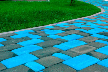 A path from a bright blue tile pavers near a juicy green lawn. Bright clinker tiles of different...