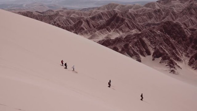 SAN PEDRO DE ATACAMA, CHILE - CIRCA DECEMBER 2017: People runs down over the sand dunes of the dead valley, Atacama desert, Chile. Slow motion