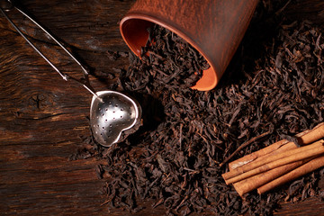tea strainer with a cup and black tea on wooden table on dark background. Selective focus