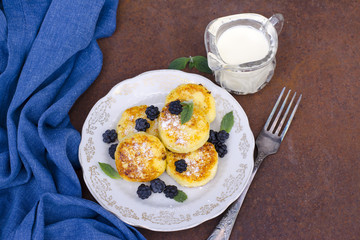 Cheese pancakes with berries. Russian cheesecakes on a metal background