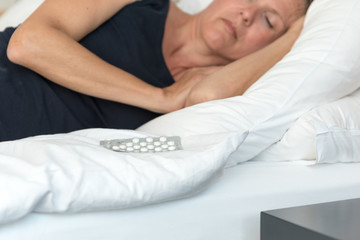 Obraz na płótnie Canvas Frau mit Schlaf Tabletten im Bett