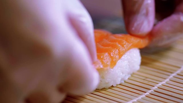 Preparing Sake nigiri sushi - fresh salmon over rice