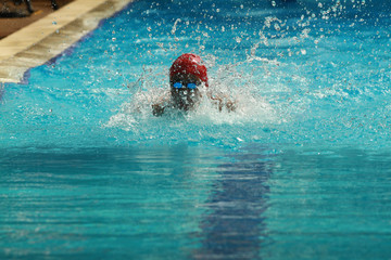 Fototapeta na wymiar Swimmer wearing red cap practice butterfly stroke in a swimming pool for competition or race