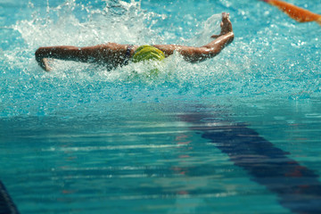 Swimmer wearing yellow cap practice butterfly stroke in a swimming pool for competition or race