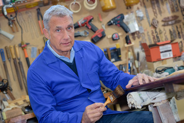 portrait of retired carpenter sitting at his workshop