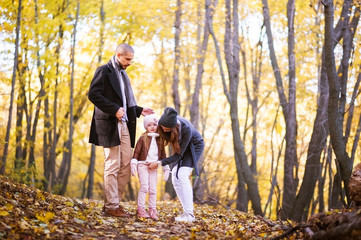Autumn fashion for children and the whole family. Mom, dad and child in the background of a yellow autumn forest