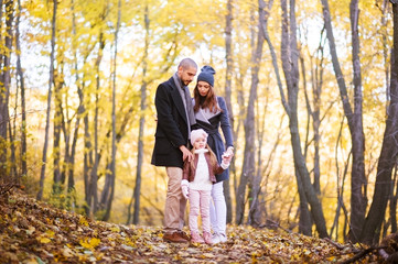 Autumn fashion for children and the whole family. Mom, dad and child in the background of a yellow autumn forest