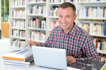 Portrait of man with books and laptop