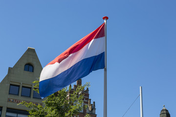 The national flag of the Kingdom of the Netherlands is developing in the wind against the sky