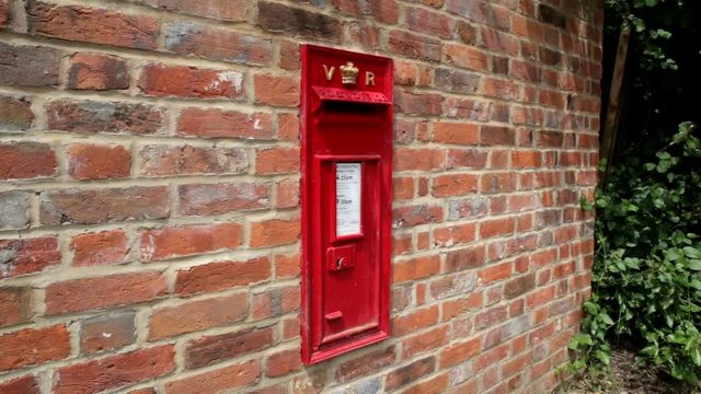 Victorian rural post box in red brick wall with greenery