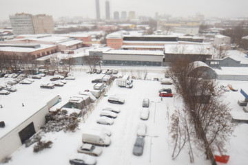Moscow, Russia. Maryina roshcha district. Top view of the cars in the parking lot covered with snow. In the background, the industrial zone and factories
