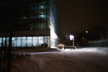 Moscow, Russia. Lighting equipment for filming is on the street on a winter evening. The building has lights on. Glass case