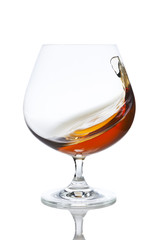 Wave of brandy in a glass isolated on white background
