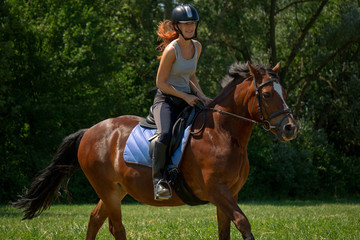 Frau model Rieterin reitet auf Pferd auf Wiese in der Natur bei Sonnenschein im Sommer