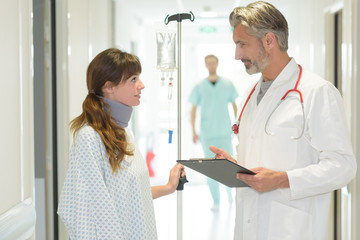 Fototapeta premium Doctor talking to patient in hospital corridor