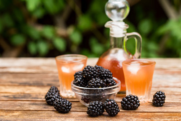 Fresh blackberries and liqueur on wooden table