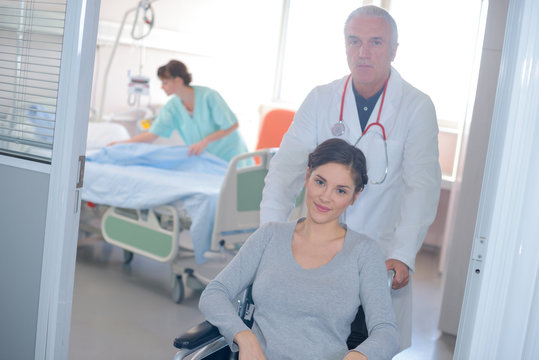 Doctor pushing female patient in wheelchair