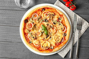 Plate with tasty pizza on wooden table, top view