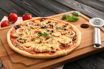 Cutting board with tasty pizza on wooden table
