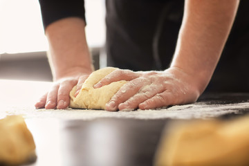 Baker kneading dough on kitchen table