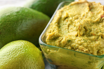 Bowl with delicious guacamole on table, closeup