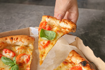 Young woman taking slice of  delicious pizza Margherita from box