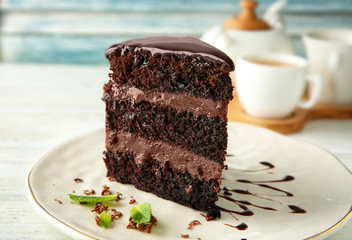 Plate with piece of delicious chocolate cake on light table