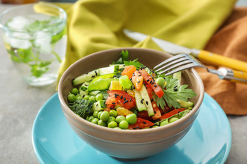 Vegetable salad with fresh green peas in bowl on table