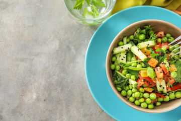 Vegetable salad with fresh green peas in bowl on grey textured background