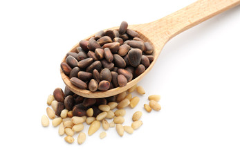 Wooden spoon with tasty pine nuts on white background