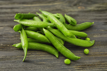 Pods with fresh green peas on wooden background