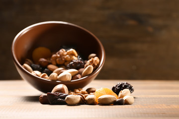 Bowl with different nuts and dried fruits on wooden table