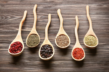 Spoons with different dry spices on wooden  background