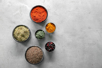 Bowls with different dry spices on light background