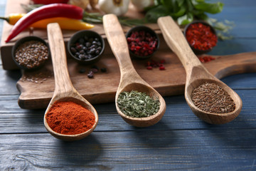 Spoons with different spices on wooden table